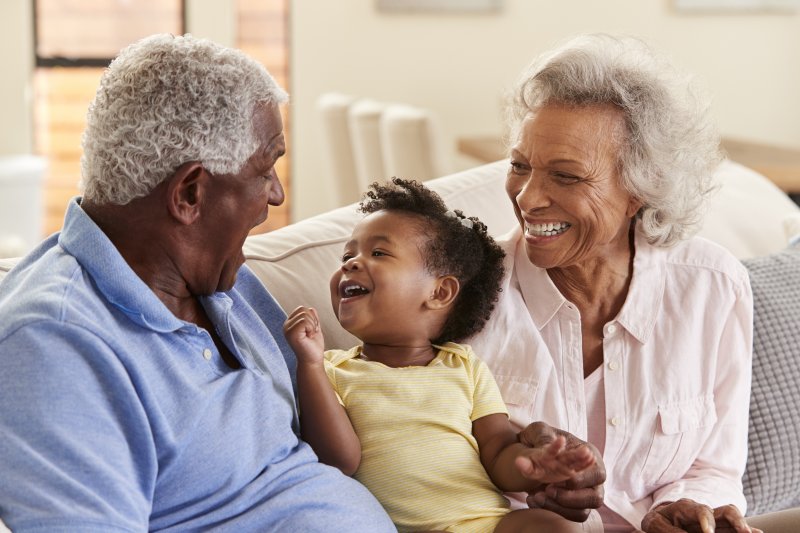 Grandparents Sitting On Sofa At Home Playing With Baby Granddaughter 8 things to consider buy hearing aids