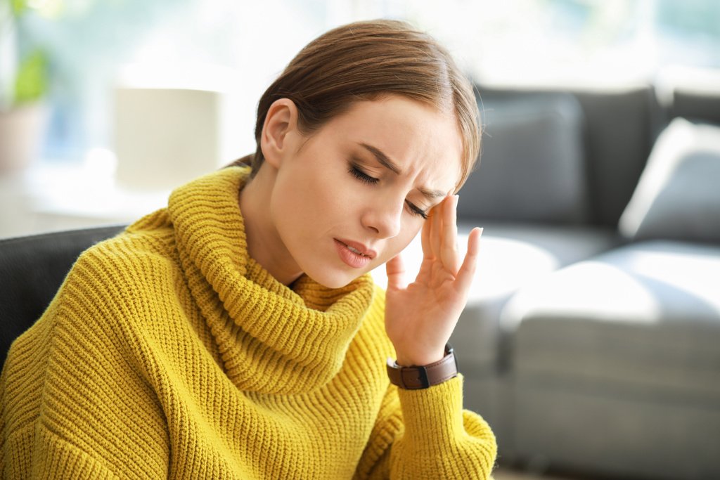 Young woman suffering from headache at home