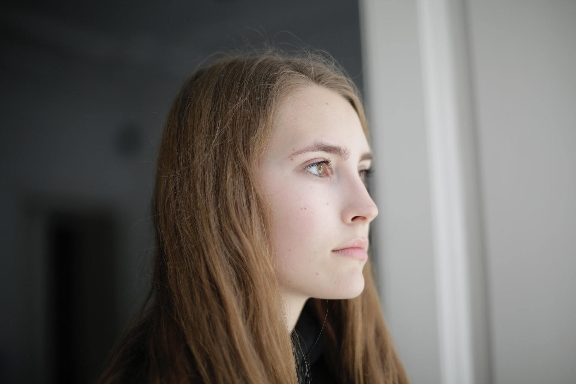 Woman Looking Out The Window - Hearing Aid Alternatives