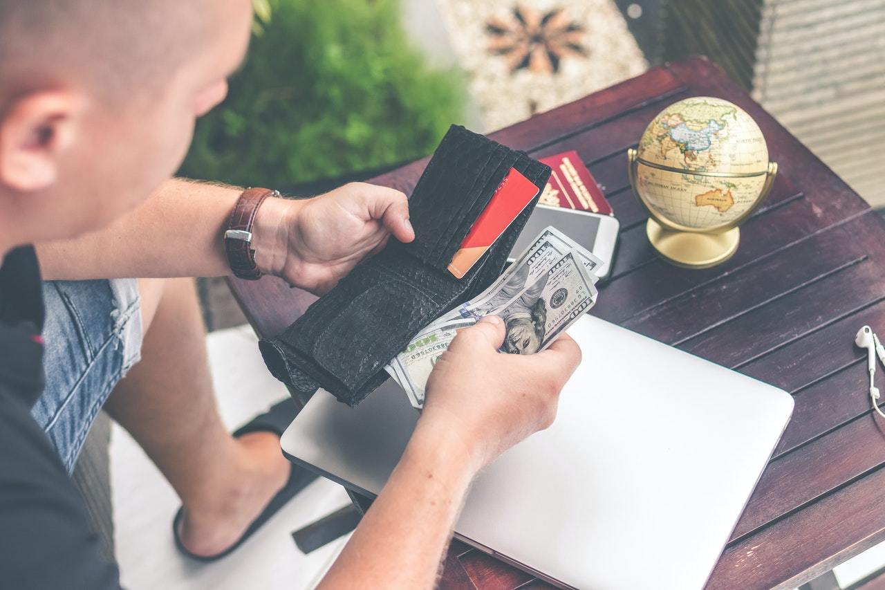 Man Looking At Wallet Considering Expensive Hearing Aid Costs