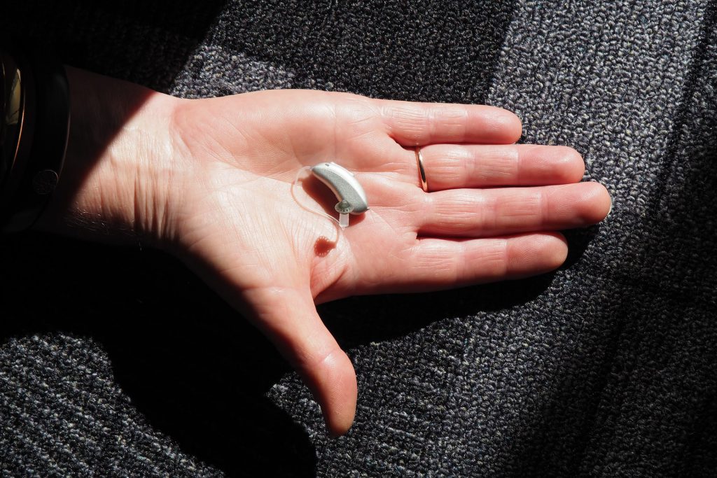 hearing aid in hand blue cross blue shield hearing aid